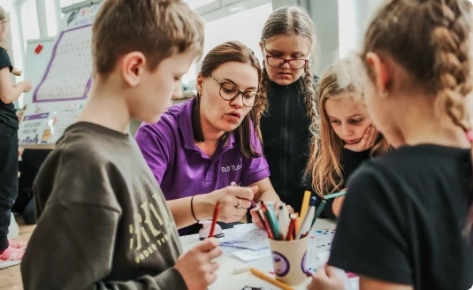 Nauczyciel dynamicznie prezentuje materiał edukacyjny zaciekawionej grupie uczniów. Dzięki profesjonalnym metodom nauczania na platformie Tutore, dzieci zyskują dogłębne zrozumienie tematu i angażują się w proces uczenia się.